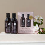 The Hair Volume™ Shampoo & Conditioner duo package displayed with white and yellow flowers.