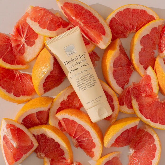 Herbal Joy™ Anti-Ageing Hand Cream displayed with freshly cut grape fruit.