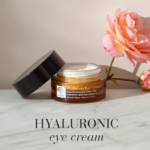 The Hyaluronic Active™ Eye Cream displayed with a pink rose on a marble table.