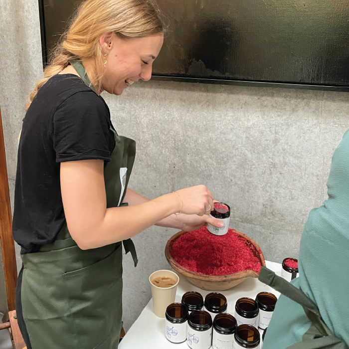 Woman experimenting with herbs at a herbal school event, learning about and engaging with plants.