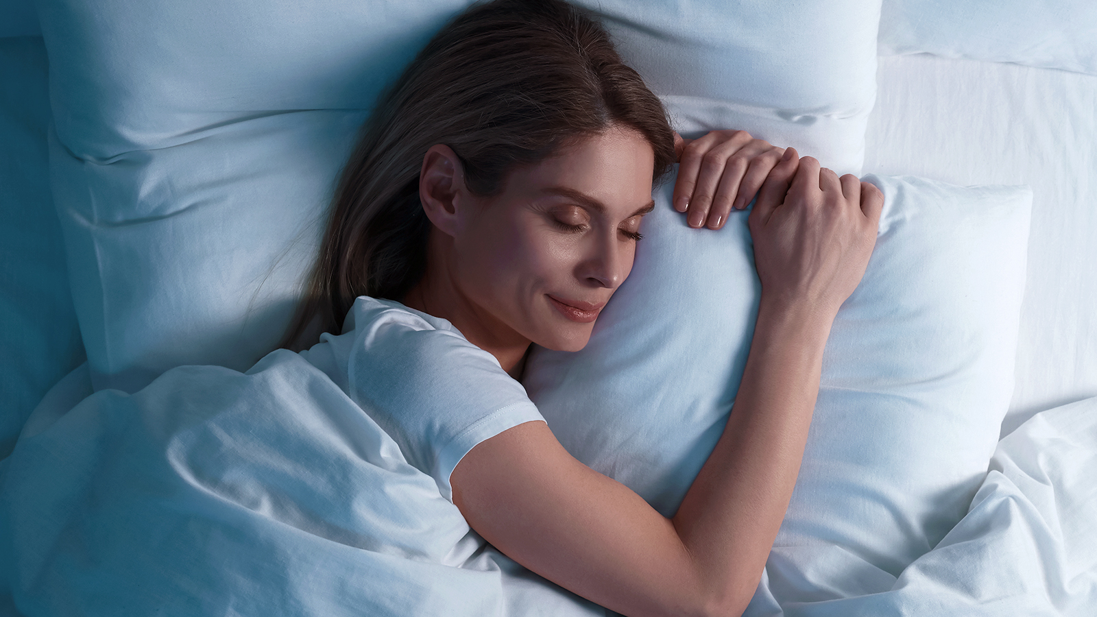 Woman sleeping peacefully in bed with her head resting on a pillow.